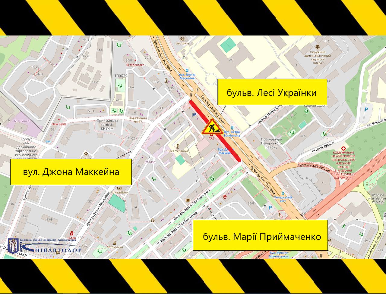 Карта в центрі Києва. Жовтими табличками підписані вулиці Джона Маккейна, бульвар Лесі Українки та бульвар Марії Примаченко. На перехресті між ними червоним кольором позначено ділянку дороги з ремонтними роботами, поруч стоїть знак «роботи на дорозі». Верх і низ картинки обрамлені жовто-чорною стрічкою попередження.